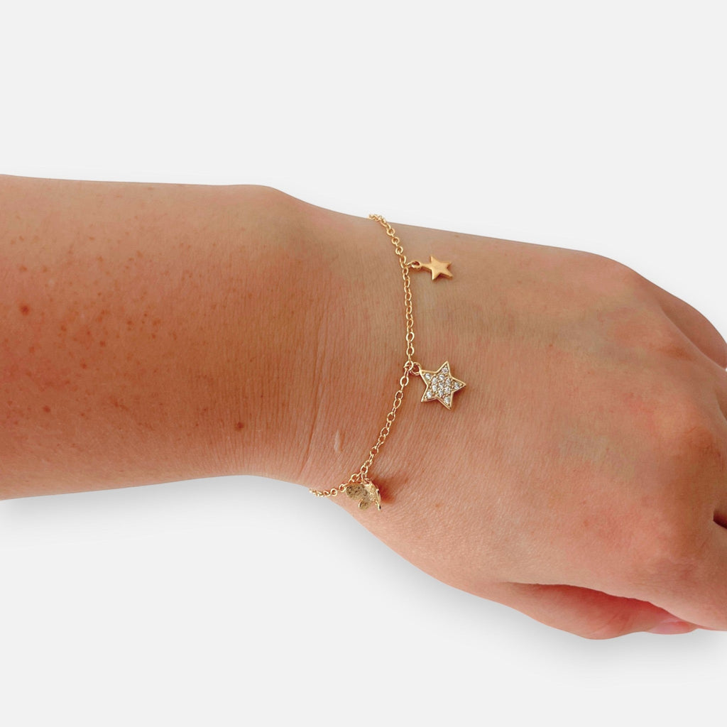 Pulsera Hv Hermanas Villegas en oro rosa con dijes de estrellas, una de ellas con circones brillantes