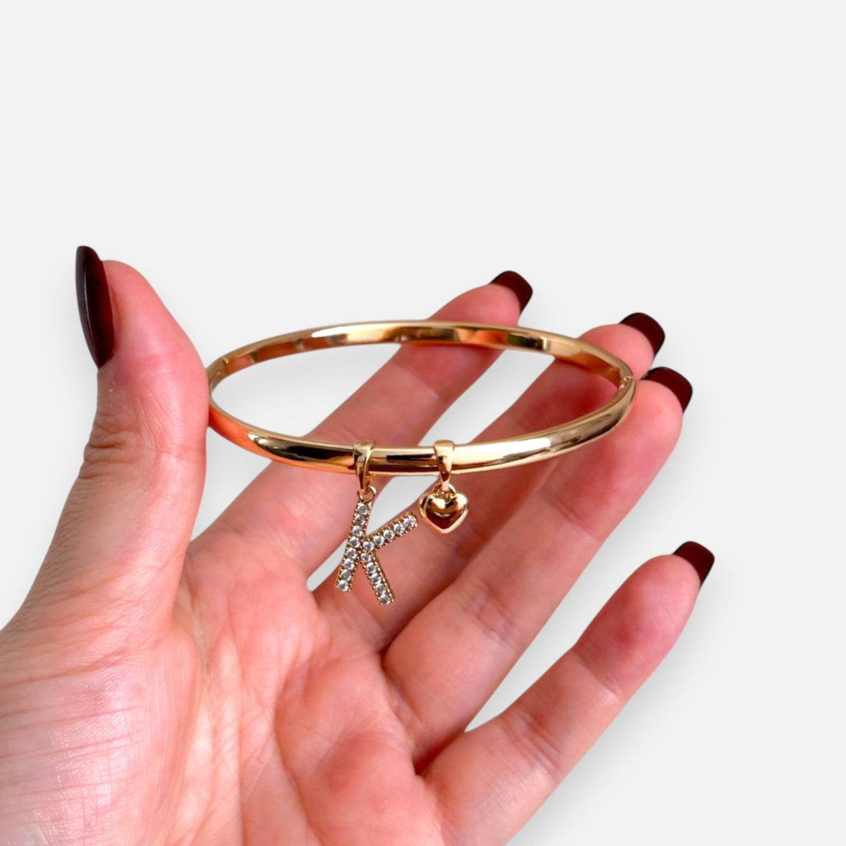 Pulsera rígida Hv Hermanas Villegas en oro rosé con dije de inicial K con circonitas y un pequeño corazón colgante