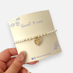 Pulsera Hv Hermanas Villegas de perlas con dije de corazón, Virgen de Guadalupe en acero dorado y circones brillantes