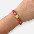 Pulsera Hv Hermanas Villegas de hilo con medalla de San Benito dorada y ojos turcos rojos de protección