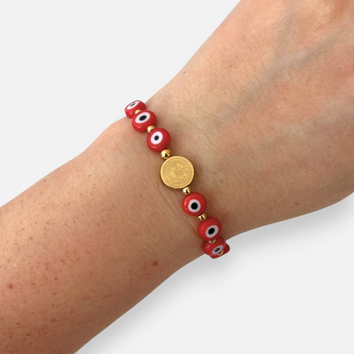 Pulsera Hv Hermanas Villegas de hilo con medalla de San Benito dorada y ojos turcos rojos de protección