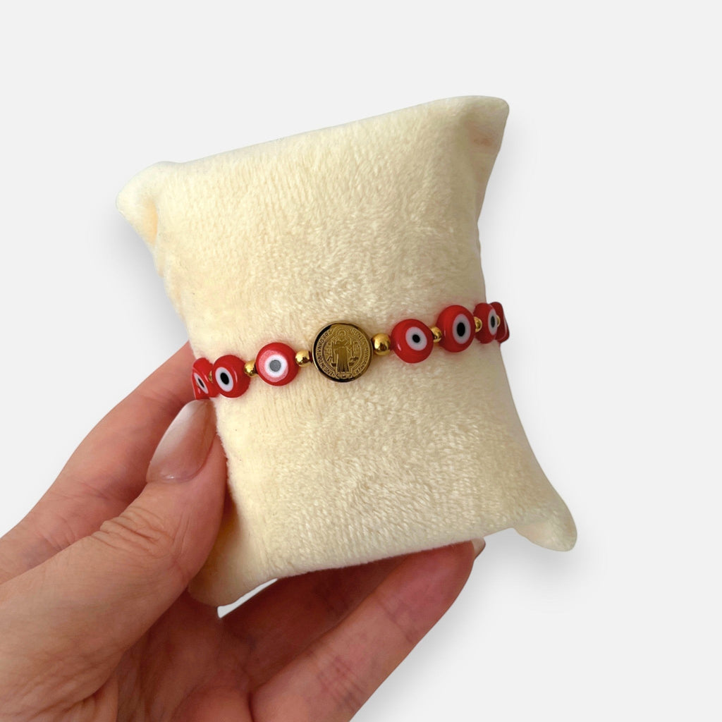 Pulsera Hv Hermanas Villegas de hilo rojo con medalla de San Benito y ojos turcos en acero dorado