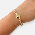Pulsera Hv Hermanas Villegas de hilo con cuentas Murano rosa, dije de San Benito en acero dorado y circones brillantes