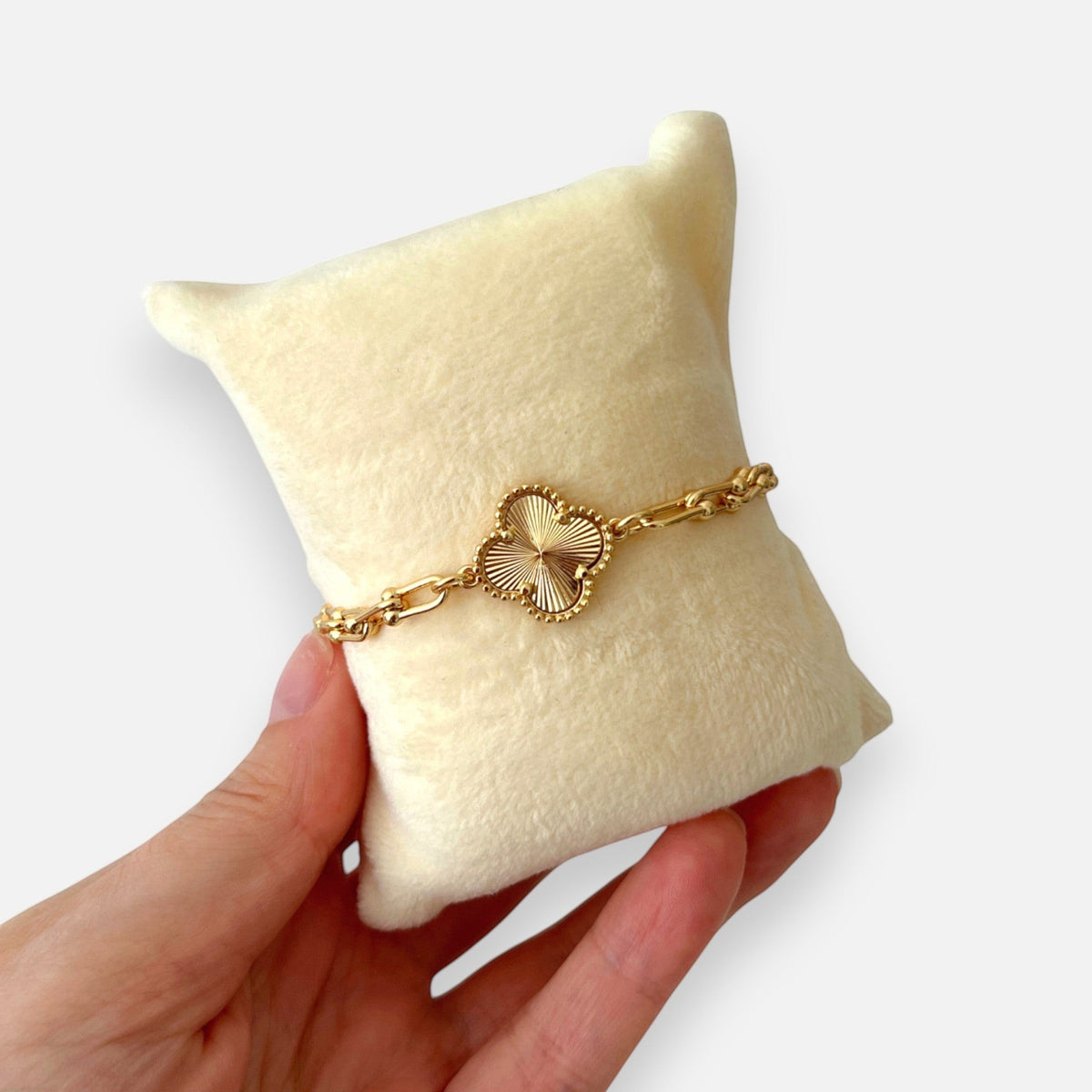 Pulsera Hv Hermanas Villegas de acero dorado con dije de trébol texturizado y cadena de eslabones tipo Tiffany