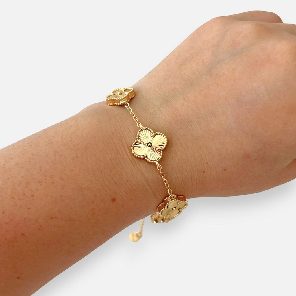 Pulsera Hv Hermanas Villegas de acero dorado con cinco dijes de trébol texturizados y borde perlado