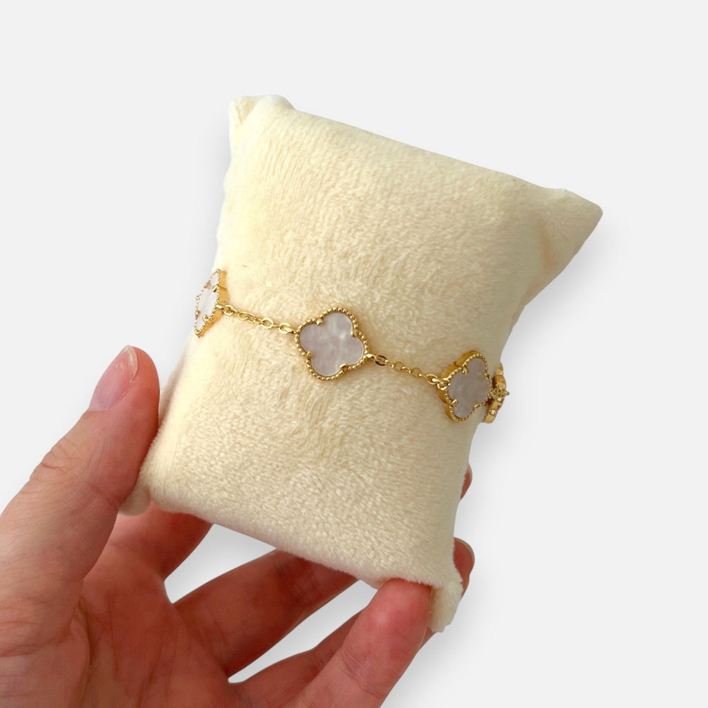 Pulsera Hv Hermanas Villegas de acero dorado con dijes de tréboles de cuatro hojas y acabado nacarado iridiscente.