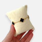Pulsera Hv Hermanas Villegas de acero dorado con dijes de tréboles negros y borde perlado