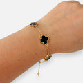 Pulsera Hv Hermanas Villegas de acero dorado con dijes de tréboles negros y borde perlado