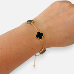 Pulsera Hv Hermanas Villegas de acero dorado con dijes de tréboles negros y borde perlado