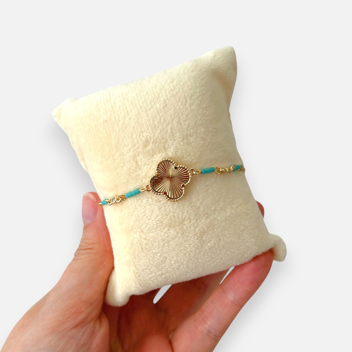 Pulsera Hv Hermanas Villegas de acero dorado con dije de trébol texturizado y cuentas turquesa