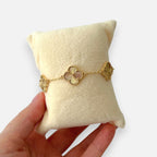 Pulsera Hv Hermanas Villegas de acero dorado con dijes de tréboles texturizados y borde perlado