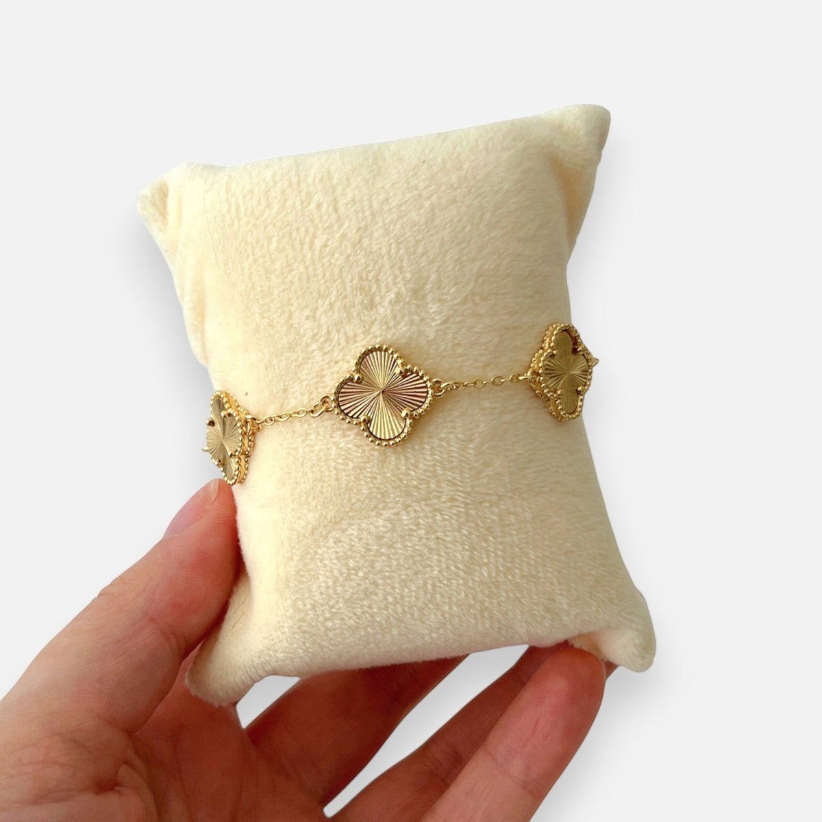 Pulsera Hv Hermanas Villegas de acero dorado con dijes de tréboles texturizados y borde perlado