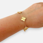 Pulsera Hv Hermanas Villegas de acero dorado con dijes de tréboles texturizados y borde perlado