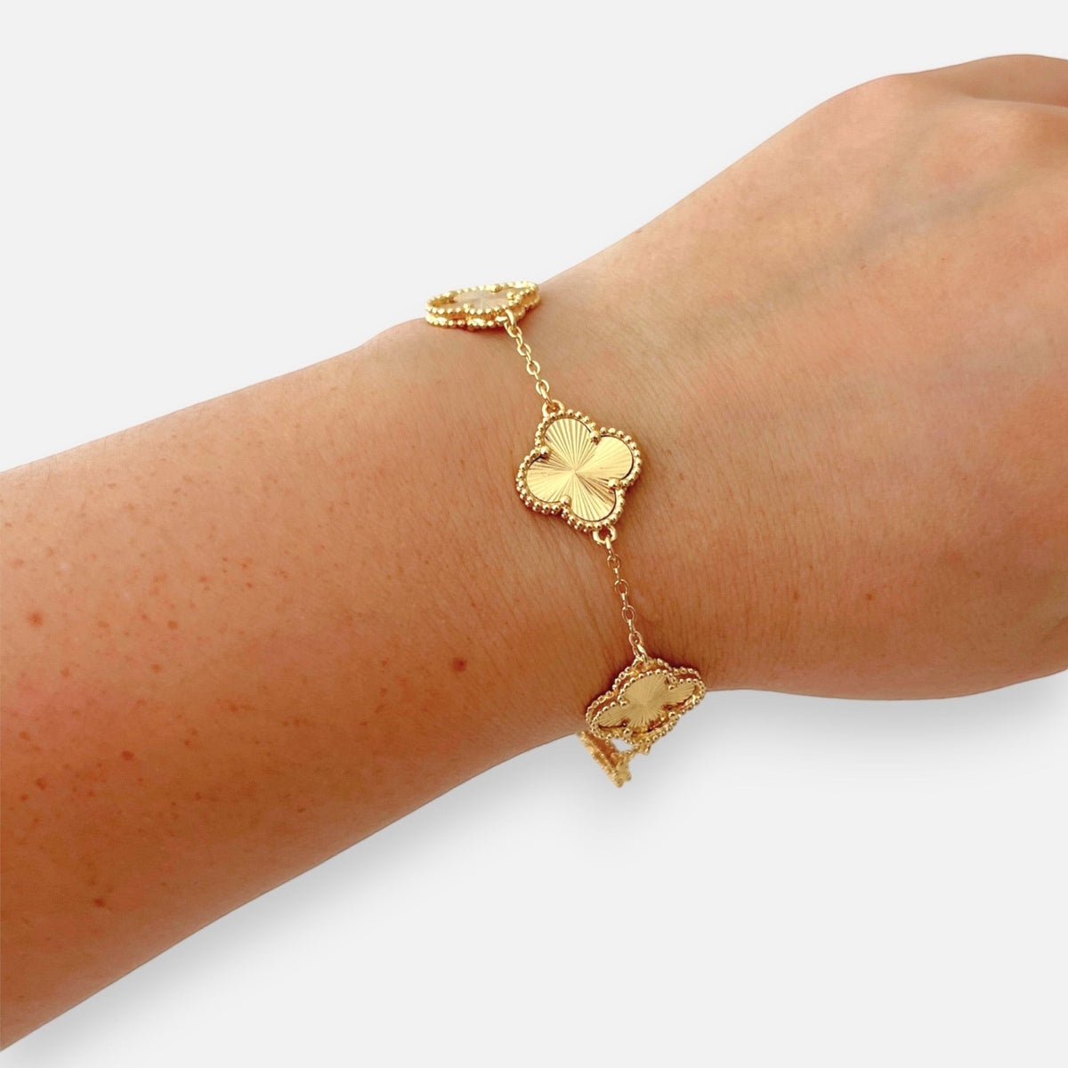 Pulsera Hv Hermanas Villegas de acero dorado con dijes de tréboles texturizados y borde perlado