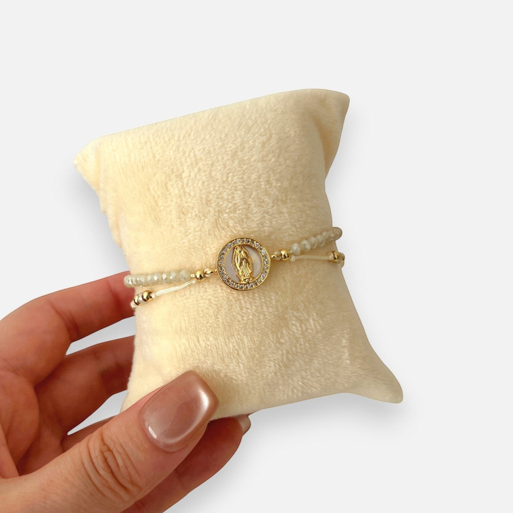 Pulsera Hv Hermanas Villegas de hilo beige con Virgen de Guadalupe en nácar, cristales Murano y acero dorado.
