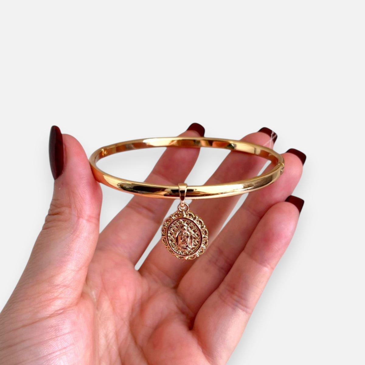 Pulsera rígida Hv Hermanas Villegas en cobre con baño de oro rosé y medalla ovalada de la Virgen de Guadalupe.