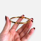 Puñera rígida Hv Hermanas Villegas en acero inoxidable dorado con circonitas incrustadas, diseño plano y elegante.