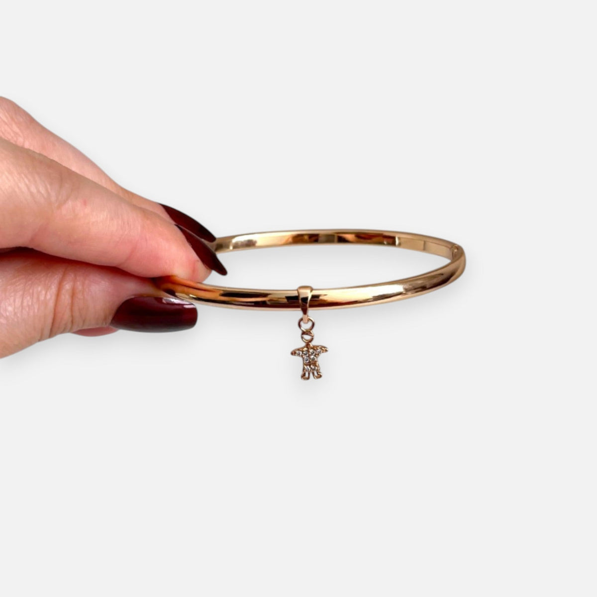 Puñera rígida Hv Hermanas Villegas en oro rosé con dije de niño y circones brillantes, diseño personalizable.