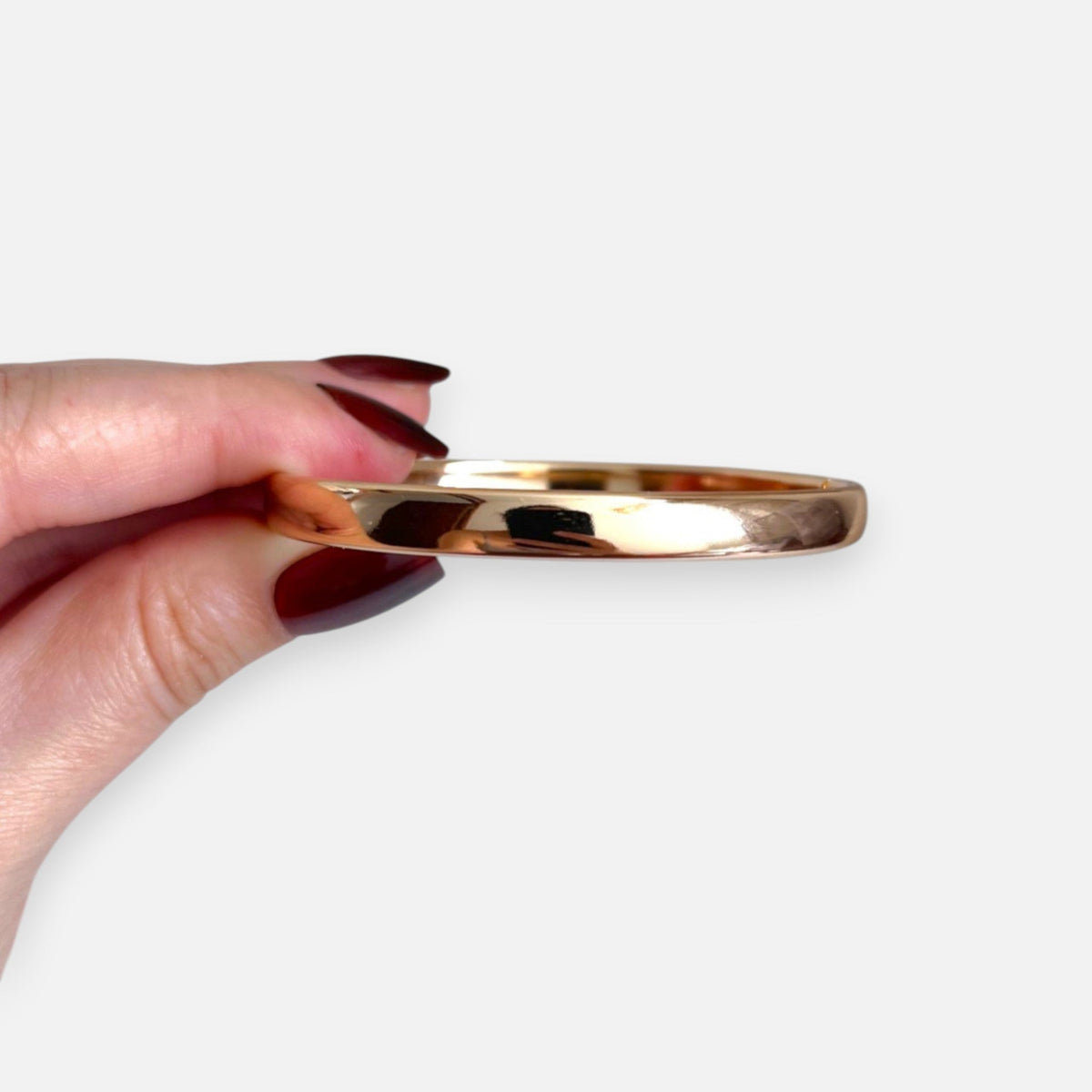 Puñera rígida Hv Hermanas Villegas de cobre con enchapado en oro rosé, diseño liso y brillante sostenida en mano.