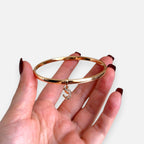 Puñera rígida Hv Hermanas Villegas en oro rosé con dije de Virgen y circonitas brillantes sobre mano femenina
