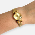 Reloj analógico Hv Hermanas Villegas de acero dorado con esfera redonda, marcadores brillantes y correa de eslabones.