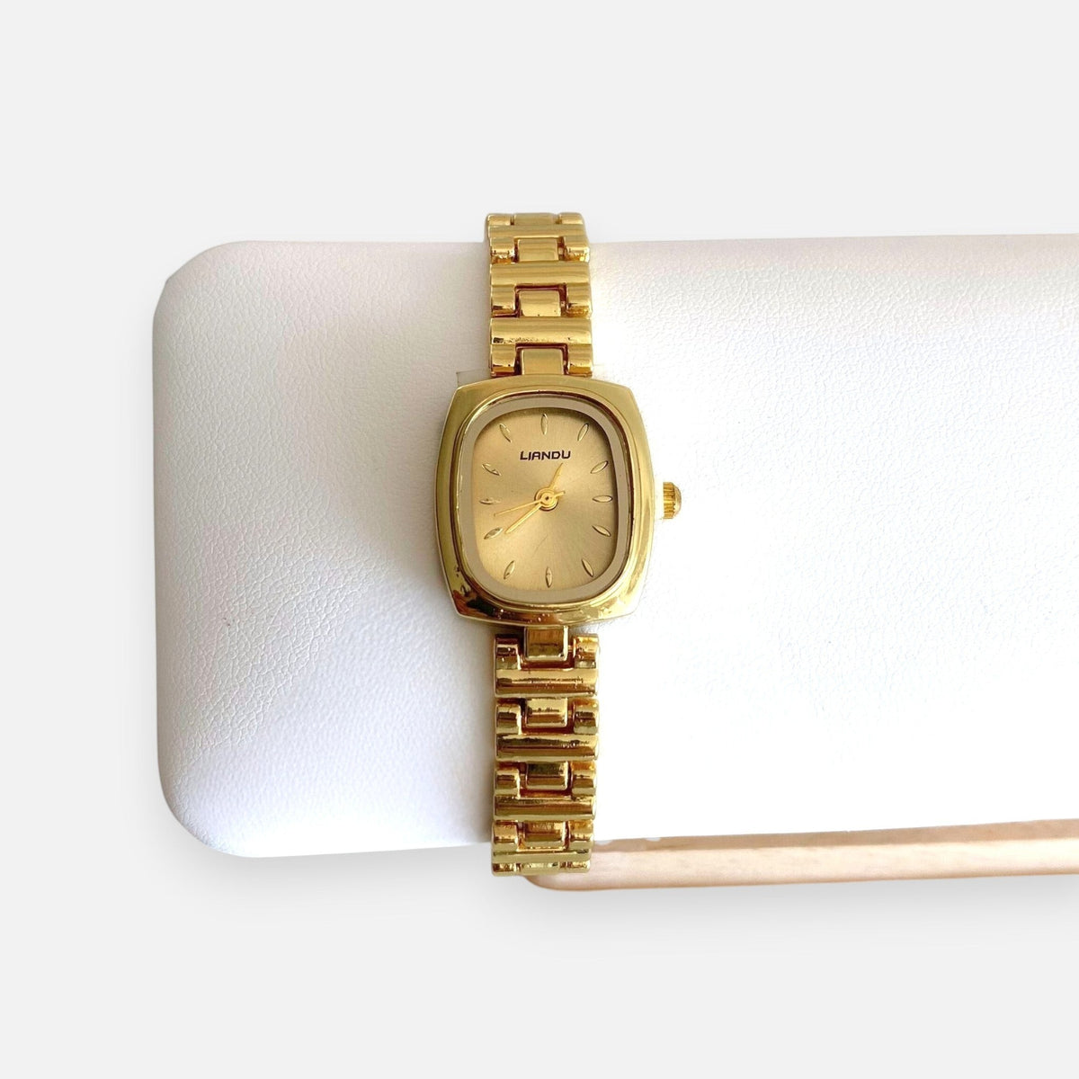 Reloj analógico Hv Hermanas Villegas con caja cuadrada dorada, dial satinado y correa de acero de estilo vintage.
