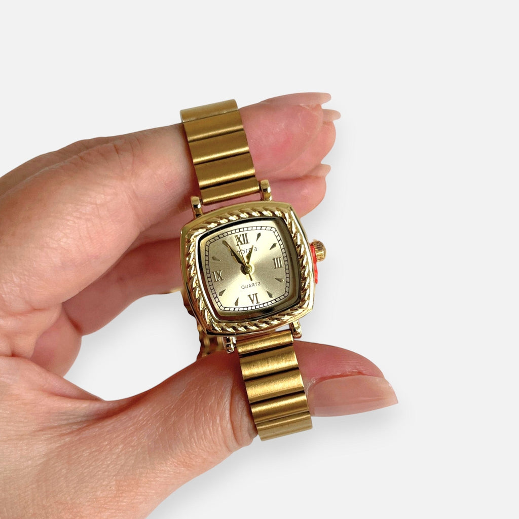 Reloj Hv Hermanas Villegas cuadrado dorado con bisel labrado, correa de eslabones y dial con números romanos