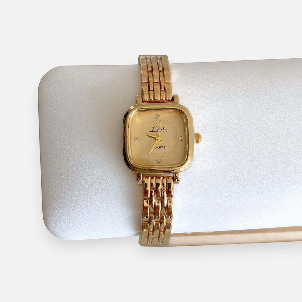 Reloj analógico Hv Hermanas Villegas de acero dorado con caja cuadrada, dial texturizado y detalles brillantes