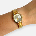 Reloj Hv Hermanas Villegas de acero dorado con caja cuadrada y dial champán cepillado en la muñeca