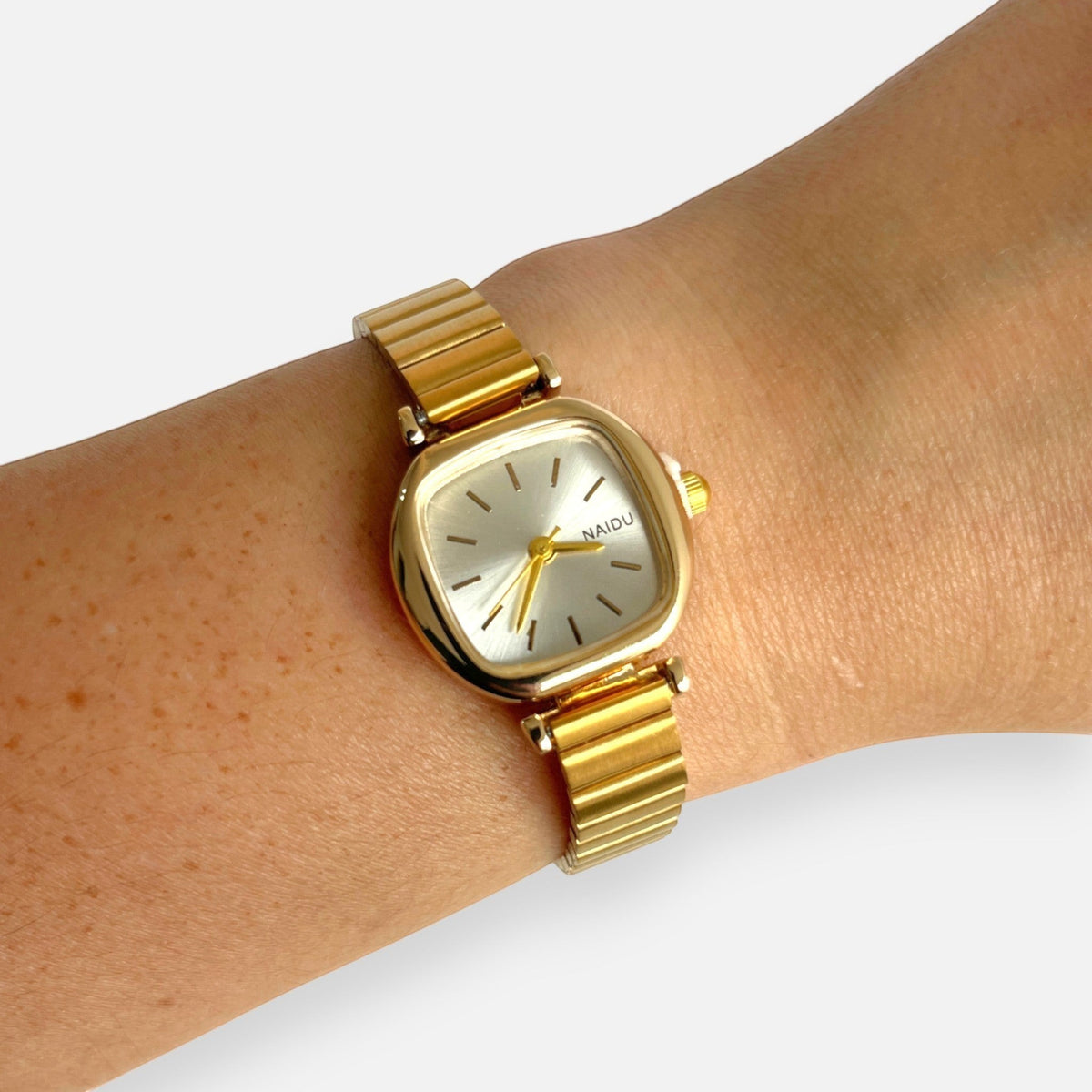 Reloj Hv Hermanas Villegas de acero dorado con caja cuadrada y dial champán cepillado en la muñeca