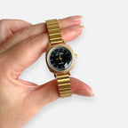 Reloj Hv Hermanas Villegas de caja cuadrada dorada, correa de eslabones y dial negro con estilo vintage elegante.