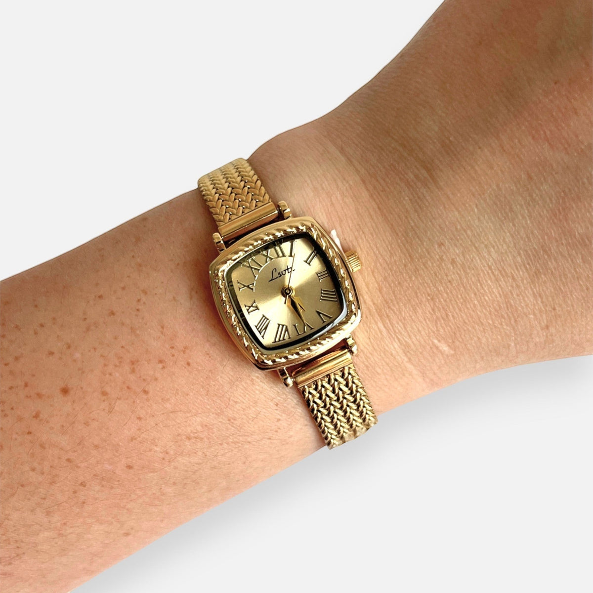 Reloj Hv Hermanas Villegas cuadrado dorado con correa trenzada y dial de números romanos en muñeca femenina