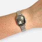 Reloj Hv Hermanas Villegas de caja cuadrada plateada, dial champán con números romanos y correa extensible flexible.