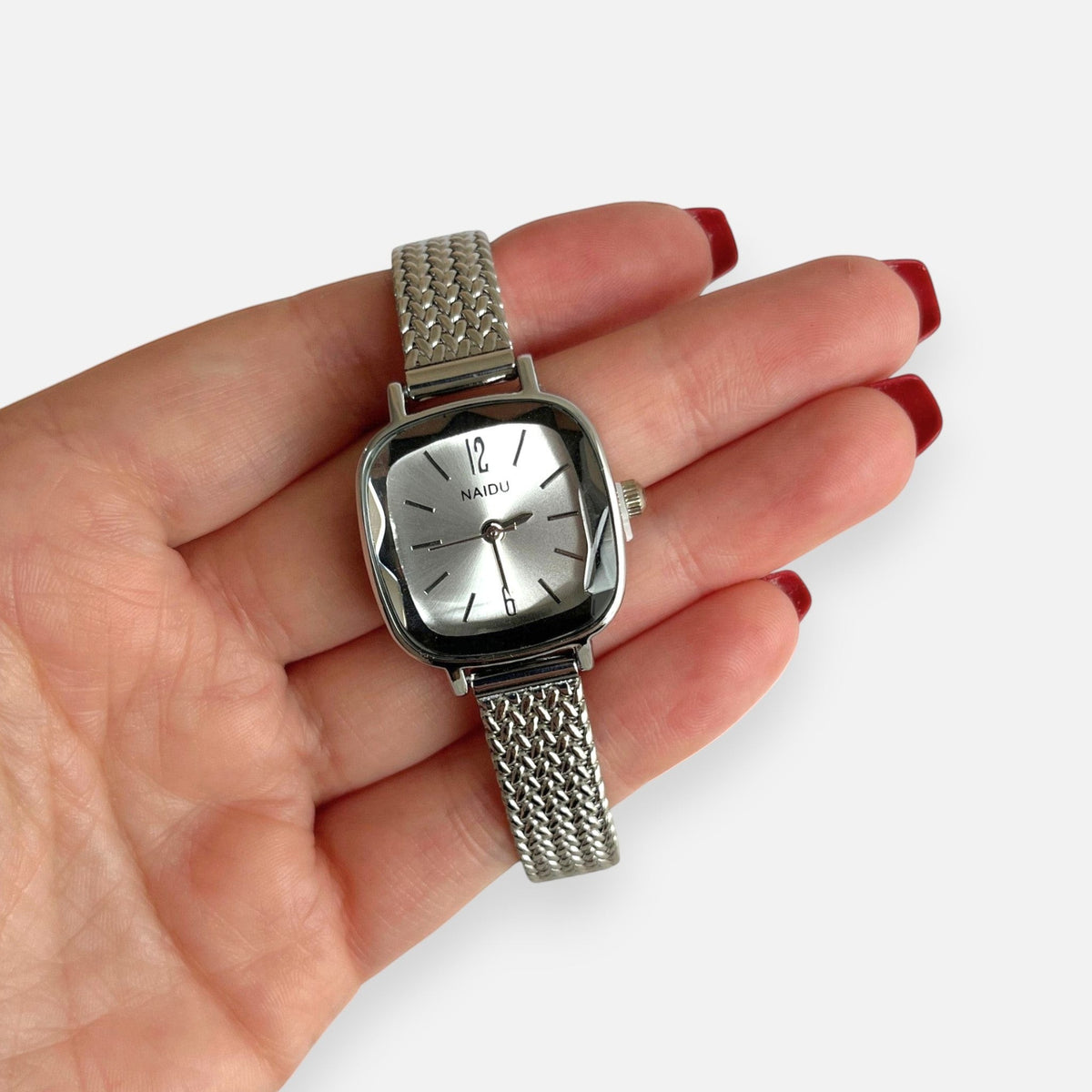 Reloj Hv Hermanas Villegas plateado con caja cuadrada, bisel labrado y correa de acero inoxidable trenzada estilo retro.