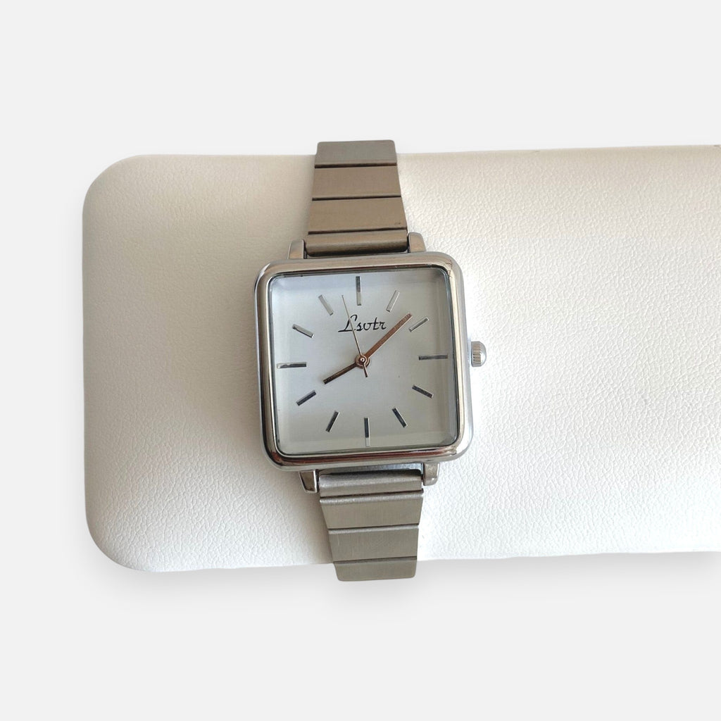 Reloj Hv Hermanas Villegas de caja cuadrada plateada, dial blanco y correa metálica extensible estilo vintage.