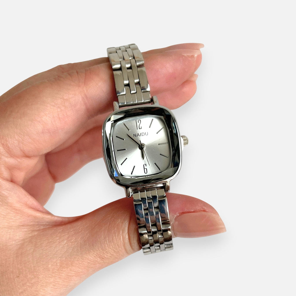 Reloj analógico Hv Hermanas Villegas de acero plateado con caja cuadrada, dial minimalista y correa de eslabones.