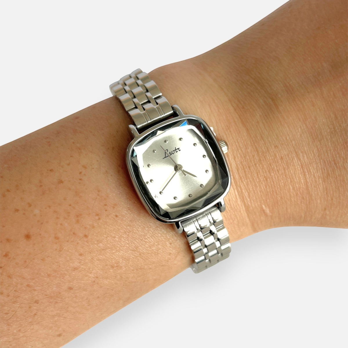 Reloj Hv Hermanas Villegas plateado con caja cuadrada, cristal biselado y correa de acero en muñeca femenina