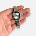 Reloj analógico Hv Hermanas Villegas de acero plateado con caja cuadrada y dial minimalista en mano femenina