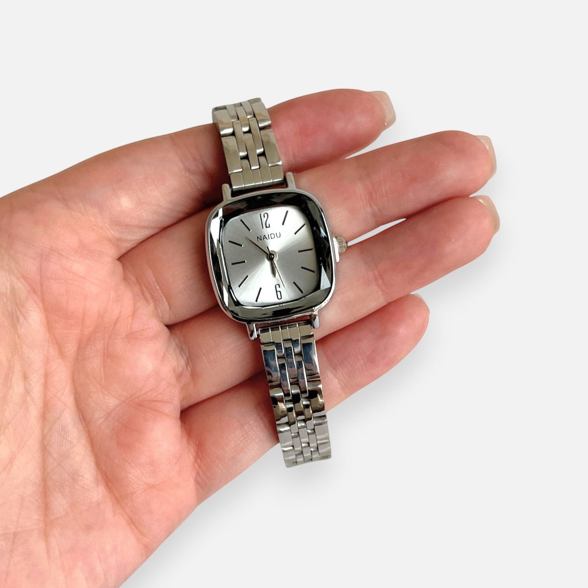 Reloj analógico Hv Hermanas Villegas de acero plateado con caja cuadrada y dial minimalista en mano femenina
