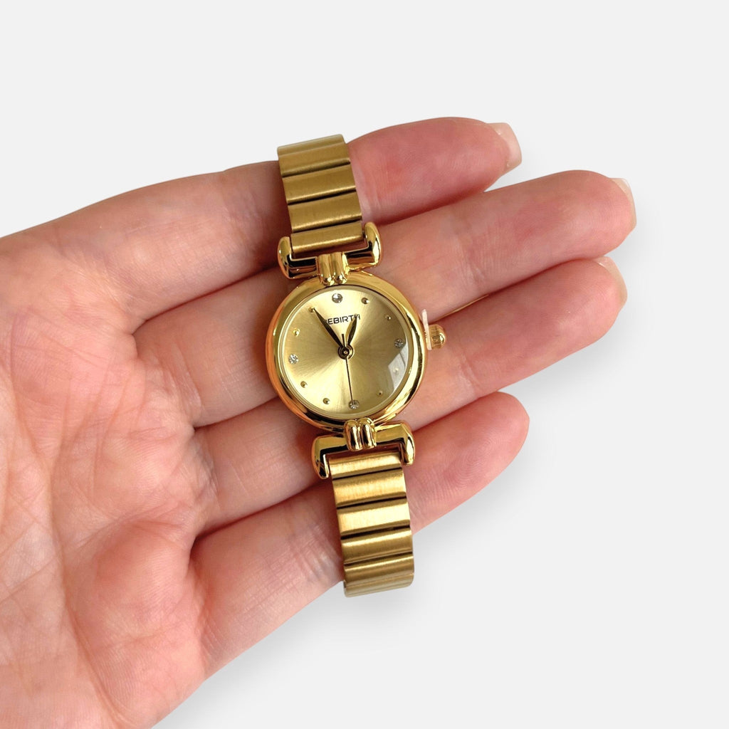 Reloj Hv Hermanas Villegas redondo dorado en acero con dial cepillado, marcadores brillantes y correa de eslabones.