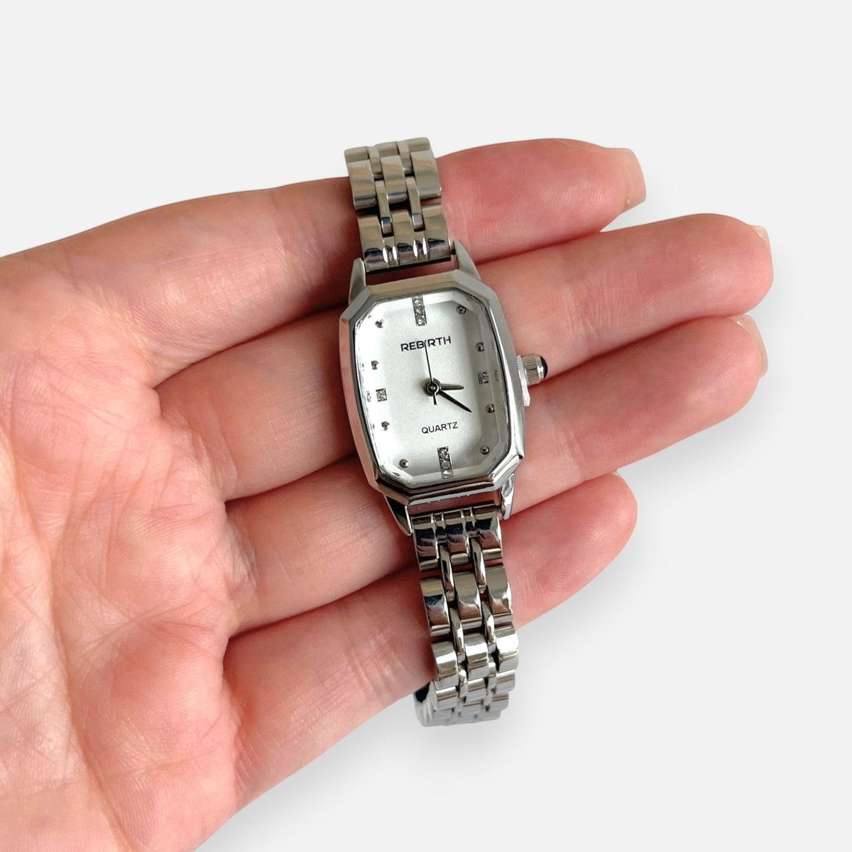 Reloj analógico Hv Hermanas Villegas de acero plateado con caja octagonal, dial claro y detalles brillantes.