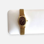 Reloj Hv Hermanas Villegas ovalado dorado con dial guinda y correa metálica extensible de estilo vintage