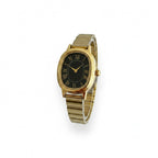 Reloj Hv Hermanas Villegas ovalado con caja dorada, dial negro y números romanos en correa de acero extensible.
