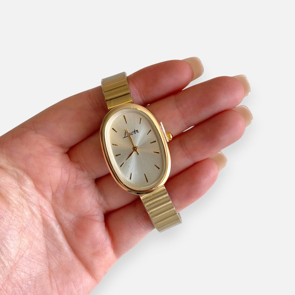 Reloj Hv Hermanas Villegas ovalado de acero dorado con correa de eslabones flexibles y dial minimalista en mano