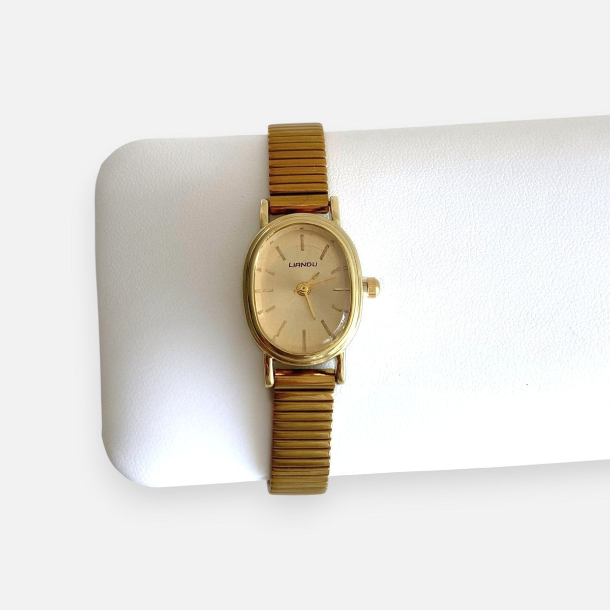 Reloj analógico Hv Hermanas Villegas con caja ovalada dorada, dial cepillado y correa metálica extensible vintage.