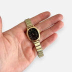 Reloj Hv Hermanas Villegas ovalado dorado con dial negro y números romanos en mano