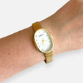 Reloj Hv Hermanas Villegas ovalado dorado con dial nacarado y marcadores de cristales en muñeca femenina
