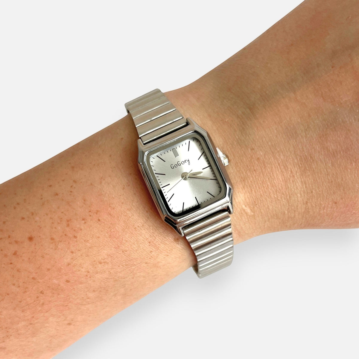 Reloj Hv Hermanas Villegas rectangular plateado con correa extensible y dial minimalista en muñeca