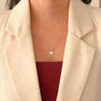 Set de joyería Hv Hermanas Villegas en plata 925 con collar de dije corazón pavé y aretes a juego sobre blazer beige